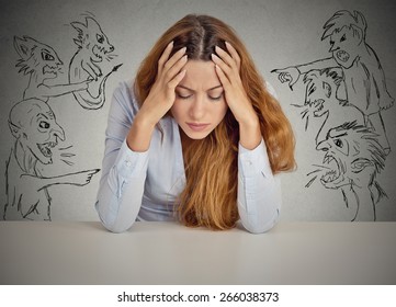 Evil Men pointing at stressed woman. Desperate young businesswoman sitting at desk in her office isolated on grey wall background. Negative human emotions face expression feelings life perception