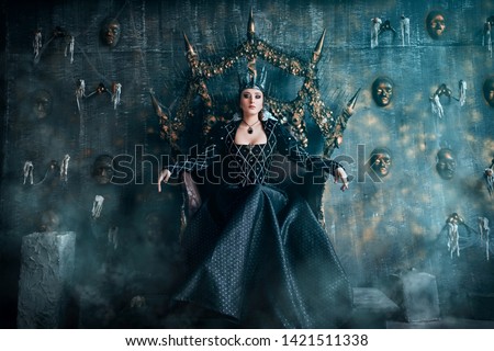 Evil Queen in a black dress. Beautiful girl in the crown sits on the throne