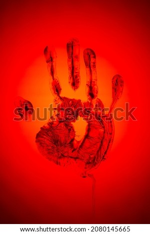 Evil red human palm imprint on red backdrop as sign of danger and warning