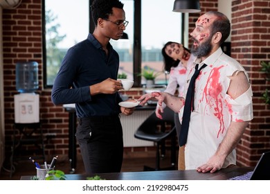 Evil Zombie Talking To Businessman In Office, Bloodthirsty Brain Eating Monster Having Conversation In Business Workplace. Walking Dead Corpse With Bloody Wounds And Sinister Scars.