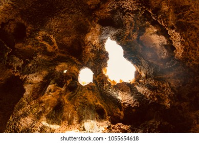 evocative interior of a cave opening on the sky in the national park of the island of Aruba in the Caribbean sea - Shutterstock ID 1055654618