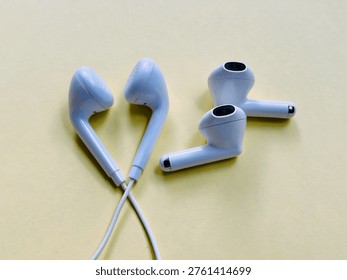 evolution of audio technology, white wired and wireless earbuds isolated on yellow