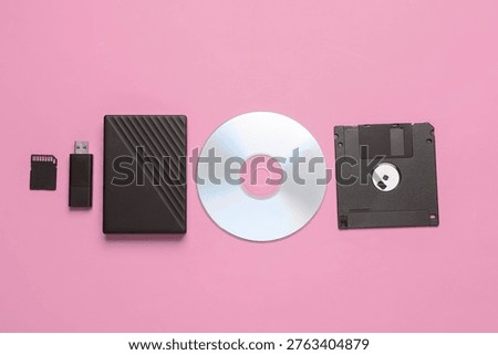 Evolution of storage media. CD disk with floppy disk, sd card, USB flash drive and external hard drive on pink background