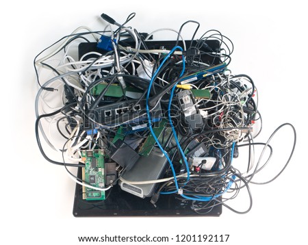 E-waste mess. A jumbled up pile of old wires cables, power adapters, circuit boards, laptop computer, cell phones isolated on White. Forming a mass of tech spaghetti.