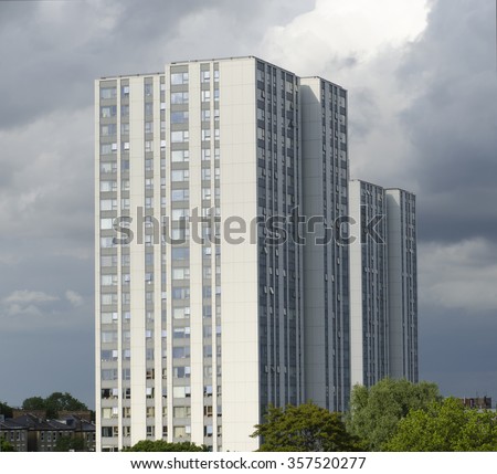 Ex local authority social housing high rise flats in north London, UK. Tower blocks stand tall basking in the late evening sun set against ominous black rain clouds.