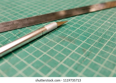 Exacto Knife And Metal Ruler On A Green Cutting Mat 