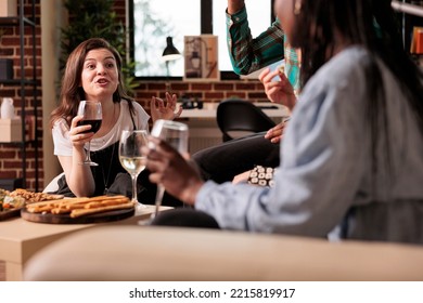 Exalted Woman Shouting, Talking Loudly Arguing To Different Ethnicities People Group At Friends Living Room Apartment Dinner, Drinking Wine, Eating Bread Sticks, Cheese.