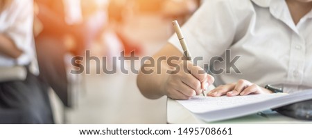 Exam at school with student's taking educational admission test in class, thinking hard, writing answer in university classroom, education and world literacy day concept