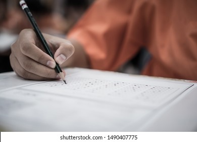 Exam Test School Or University Concept : Hand Student Holding Pencil Writing Standardized Answer Multiple Carbon Paper Form With Gray Black Answers Sheet Bubbled Doing Final Assessment In Classroom