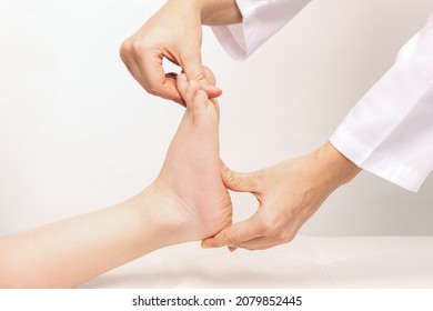 Examination of a child by an orthopedist. Cropped shot of female doctor holding a kid's foot in her hands.Pathology of bone structures, flat feet, injury. Foot treatment. Pain from uncomfortable shoes - Shutterstock ID 2079852445