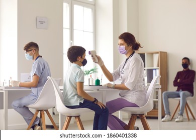 Examination at doctor's office. Nurse in face mask checking child's temperature. Young hospital worker using non-contact infrared thermometer to measure little patient's body temperature - Powered by Shutterstock