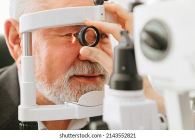 examination of elderly man with slit lamp. microscope and focused light source. device for high-precision examination of eye to determine condition of lens, cornea. medical equipment.