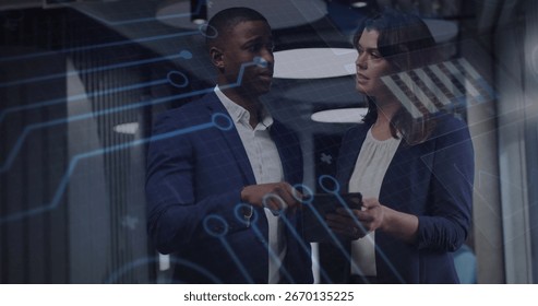 Examining data on tablet two wearing business suits in office corridor, with circuit graphic, racks. Technology, innovation, collaboration, corporate, futuristic, digital, analysis