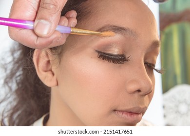An example of adding eyebrow highlights. Professional makeup technique using a highlighter. Preparing a young asian client for her debutant birthday or fashion show.