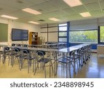 Example of an empty nondescript US High School Classroom with desks, Window and black board.	