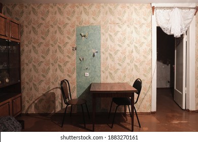 Example of Old Soviet Russian poor interior in Khruschev House. Aged  sideboard, table, chairs, sofa. Shabby floor. Tattered wallpaper on the wall. Paper butterflies as decor. Apartment of pensioners.