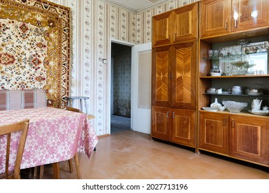 Example of Old Soviet Russian poor interior in Khruschev House. Aged  sideboard, table, chairs, sofa. Shabby floor. Tattered wallpaper on the wall. Apartment of pensioners. Selective focus.