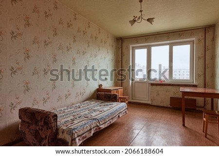 Example of Old Soviet Russian poor interior in Leningrad project House. Aged  sideboard, table, chairs, bed. Shabby floor. Tattered wallpaper on the wall. Apartment of pensioners. Selective focus.