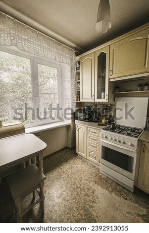 Example of Old Soviet Russian poor kitchen interior in Khruschev House. Aged stove, table. Shabby floor.  Apartment of pensioners.