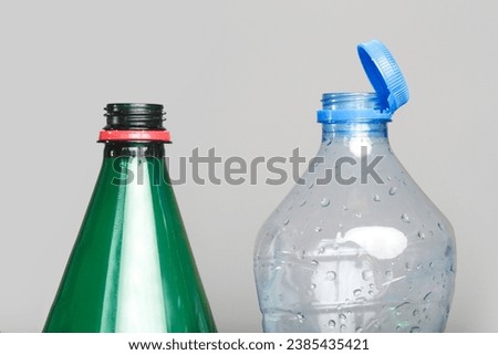 Example of older model and new cap attached to plastic bottle, connected to the neck of the bottle by solid tab attached to safety ring. 