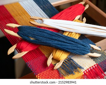 Example of tabby weave. Wooden stick shuttles with colored yarn on the hand loom. Textile production