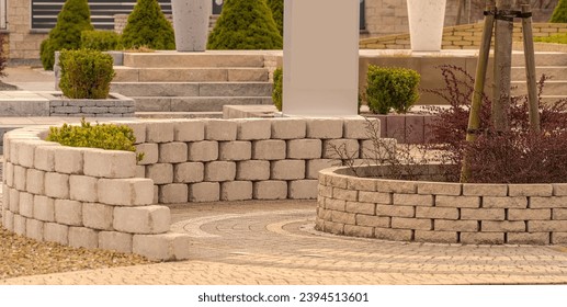 An example of the use of concrete elements in garden architecture (paving accessories).A garden with numerous concrete block elements (tiny walls, flower pots, flower beds), large flower pots .