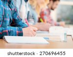 Exams. Cropped view of students writing a test in their exercise books