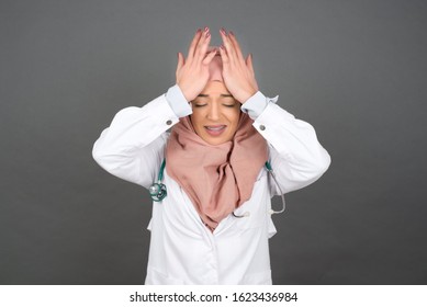 Exasperate Muslim Doctor Female Wearing Medical Keeps Hands On Temples, Feels Strong Headache, Closes Eyes With Pain, Need Healthy Sleep, Being Overworked, Fatigue And Tired.