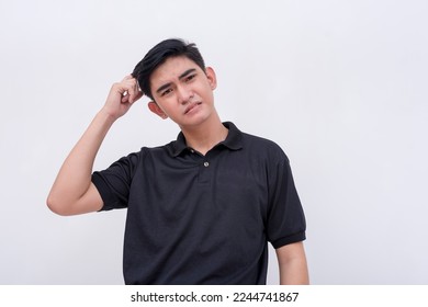An exasperated young asian man scratching his head. Regretting a mistake he made. Isolated on a white background.