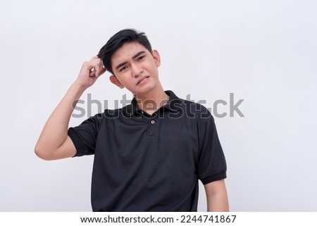 An exasperated young asian man scratching his head. Regretting a mistake he made. Isolated on a white background.