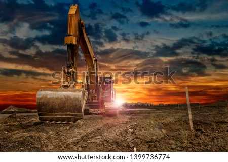 Excavating machinery at the construction site, sunset in background.