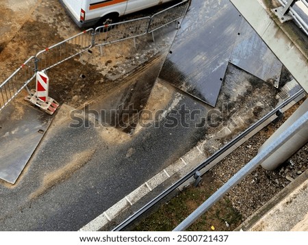 the excavation through the intersection and the road is covered with crossing plates. vehicles may drive over the repair site with caution. vertical view from above