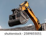 Excavator Arm with Hydraulic Bucket. Large yellow quarry excavator. Big mining truck work coal deposit. Loading coal into truck. Mining mining machinery to transport coal from open-pit production.