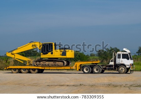 Excavator or Backhoe on the truck hauls stopping in site construction. Heavy transport truck