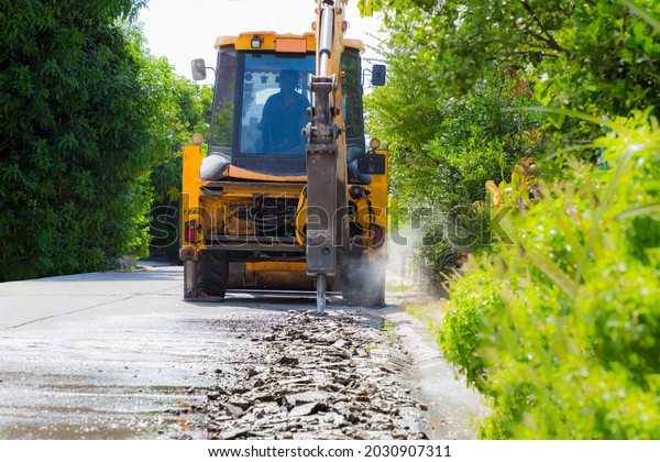 Excavator breaking and drilling the concrete\
road for repairing. Large pneumatic hammer mounted on the hydraulic\
arm of a construction equipment. Construction Vehicles repairing\
road. drill\
jackhammer