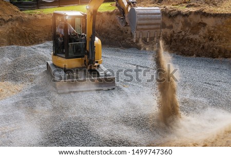 Excavator bucket moving gravel stones for foundation building working on a construction site