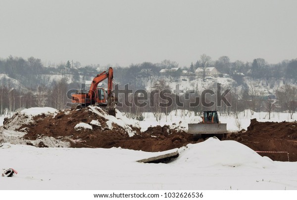 Excavator and bulldozer in the parking lot before\
work starts