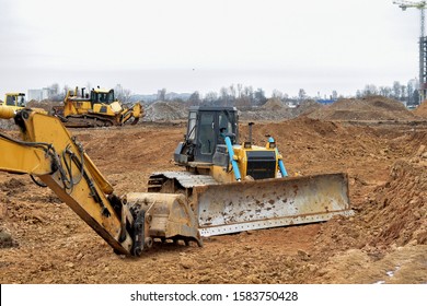 Excavator And A Bulldozer Work At A Construction Site. Land Clearing, Grading, Pool Excavation, Utility Trenching And Foundation Digging.  Laying Of Underground Storm Sewer Pipes. 