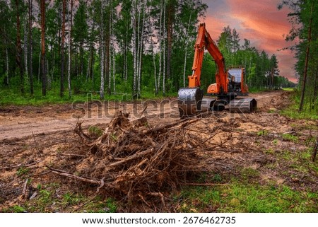 Excavator clearing forest for new development. Orange Backhoe modified for forestry work. Tracked heavy power machinery for forest, peat industry. Logging, road construction in forests. Deforestation.