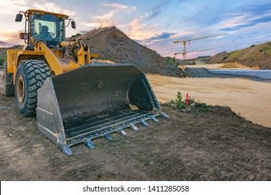 Excavator in a construction site with a crane in the background