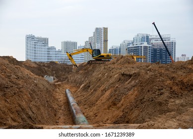 Excavator At Construction Site During Laying Sewer And Main Reticulation Systems. Civil Infrastructure Pipe, Water Lines, Sanitary Sewers And Storm Sewers. Underground Utilities Installation