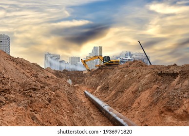 Excavator at construction site during laying sewer and main reticulation systems. Civil infrastructure pipe, water lines, sanitary sewers and storm sewers. Underground utilities installation - Shutterstock ID 1936971820