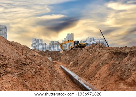 Excavator at construction site during laying sewer and main reticulation systems. Civil infrastructure pipe, water lines, sanitary sewers and storm sewers. Underground utilities installation