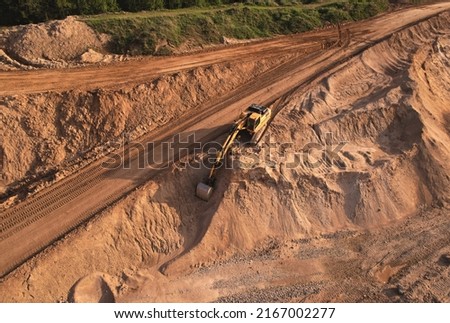 Excavator dig ground at construction site. Earthmover  on road construction. Heavy equipment and machinery. Backhoe on earthwork. Open pit development and sand extraction. Mining industry Reserves.