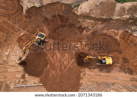 Excavator dig ground for sewerge construction. Trench for laying a concrete well ring and sewer pipe. Sewage drainage and concrete pipes. Earth-moving heavy equipment. Earthworks at construction site.