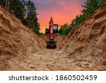 Excavator dig trench at forest area on amazing sunset background. Backgoe on earthwork for laying crude oil and natural gas pipeline or water main pipes. Construction the sewage and drainage
