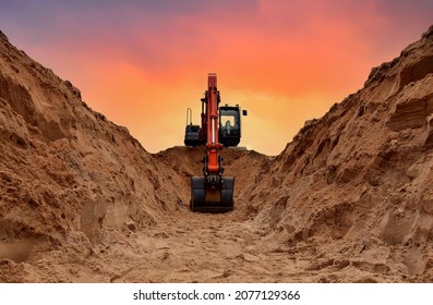 Excavator dig trench on sunset background. Backgoe on earthwork. Construction natural gas pipeline. Construction the sewage and drainage.  Laying sewer pipes at construction site. Open pit mining.