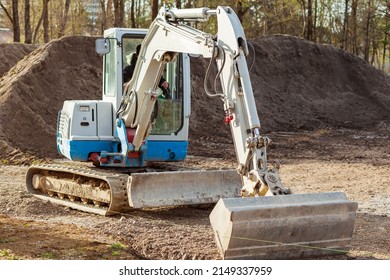 Excavator digging. Crawler Mini Excavator with wide Bucket Working on pile of soil background. Digger levels ground. Excavation Work. 