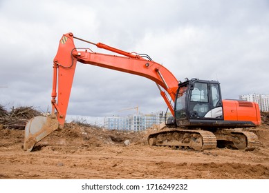 Excavator digs dirt during roadwork at construction site. Heavy machinery and earth-moving equipment