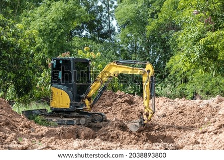 The excavator digs a soil. Digger loading trucks with soil. Excavator working on earthmoving at open pit mining. Excavator working on earthmoving at construction site.